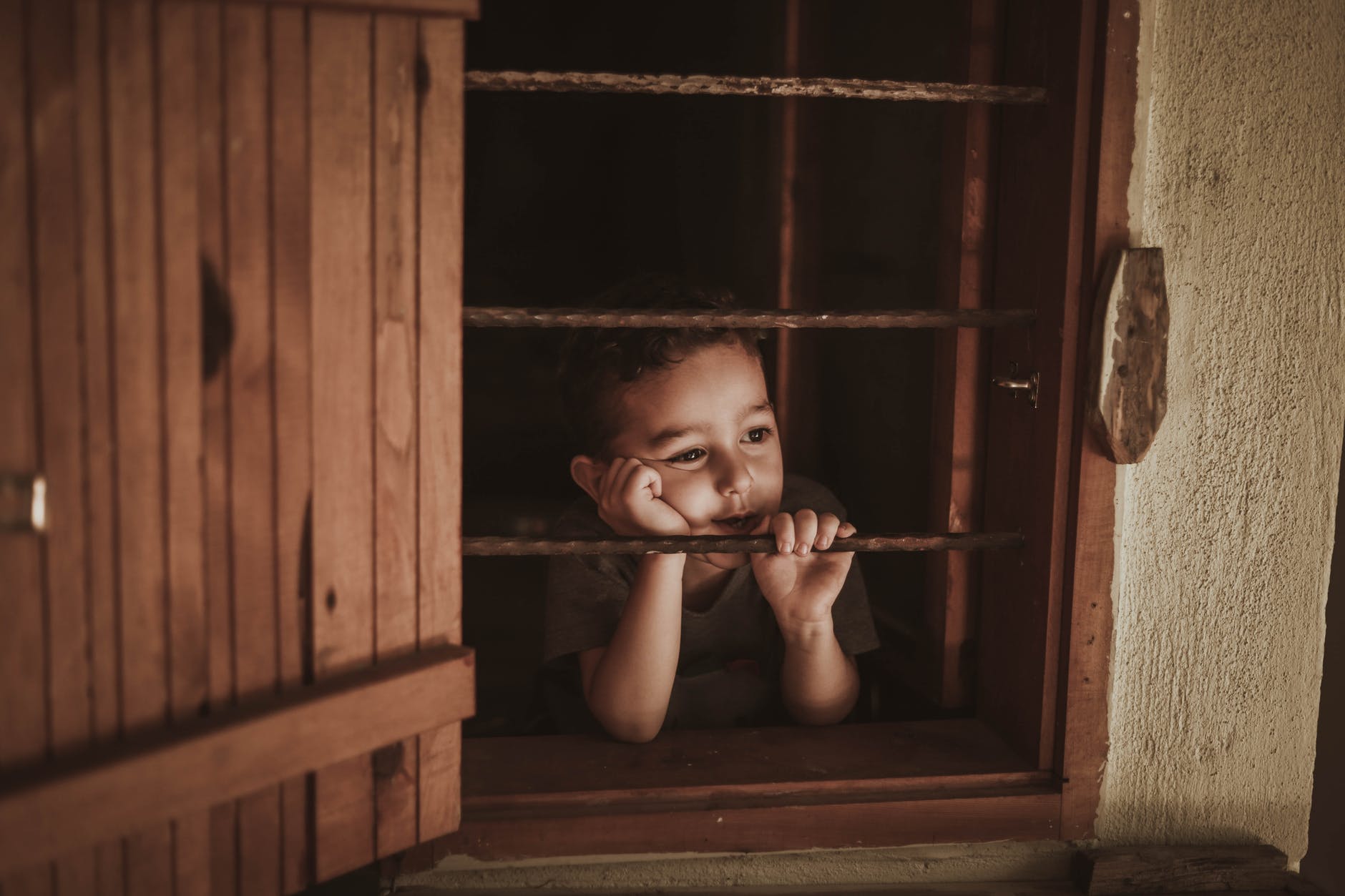 photo of boy leaning on window rails